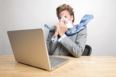 Mann am Laptop niest